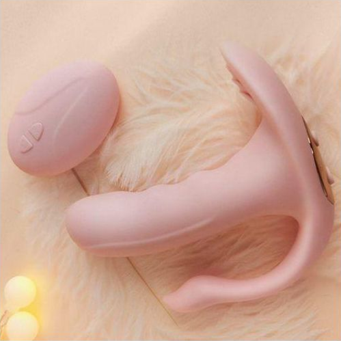 Pink handheld massager on a soft surface with a warm glow